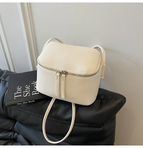 Detail einer cremeweißen Mini-Umhängetasche mit Lychee-Maserung und Doppelreißverschluss