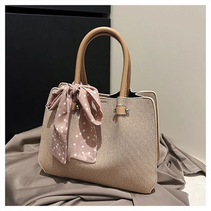 Détail du sac cabas en paille avec poignée en cuir et foulard en soie à pois roses