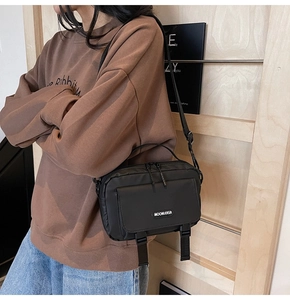 Side view of black nylon messenger bag with adjustable strap and logo on model
