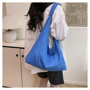 Model wearing a bright blue canvas hobo bag, showing large capacity and casual style