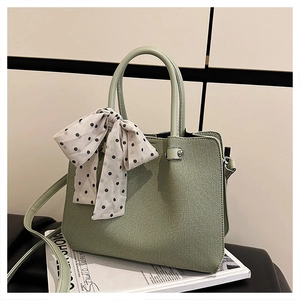 Détail du sac à main tissé vert clair avec foulard en soie à pois et pieds en métal