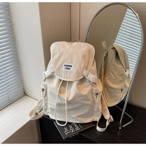 Detail view of canvas backpack with drawstring closure, flap, and side zipper pocket