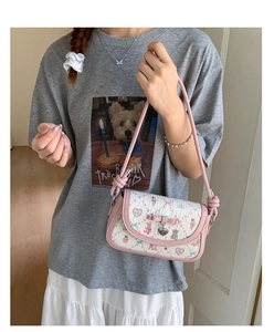 Close-up of pink bow and heart pendant on a jacquard ballet style crossbody bag