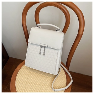 Close-up of white embossed faux leather handbag with silver ball chain on a wooden chair