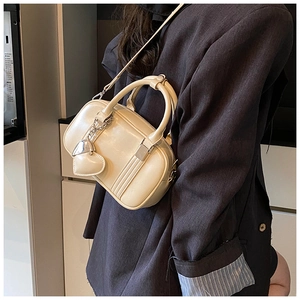Close-up of cream mini bowling bag with heart charm and silver hardware detail