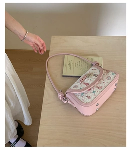 Close-up of pink ballet-style crossbody bag with floral bear prints and rivet details
