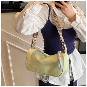 Détail macro d'un sac cylindrique vert avec bandoulière géométrique et pendentif tressé