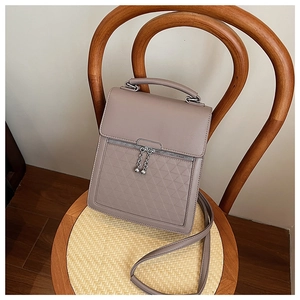 Detail of grey-purple textured handbag featuring geometric patterns on a wooden chair