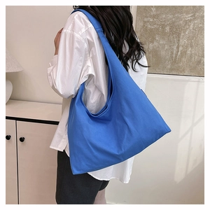 Macro view of blue canvas tote bag showing the thick durable texture and shoulder strap