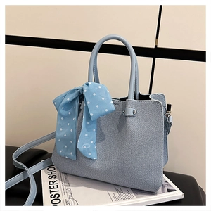 Détail du sac seau bleu clair avec ruban à pois au manche et texture en tissu fin
