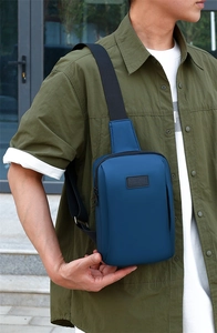 Detail of dark blue sport chest bag with embossed logo and adjustable strap worn by model