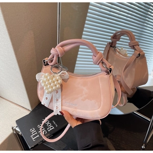 Detailed view of pink croissant bag with knotted handle and pearl lace heart charm
