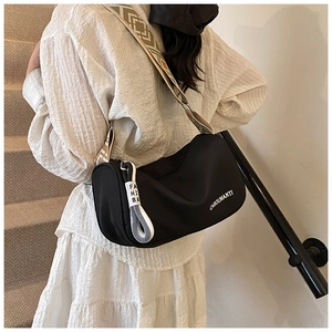 Détail du sac bandoulière en nylon noir avec sangle géométrique large et pendentif blanc