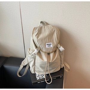 Detail of beige nylon backpack with drawstring closure and waswac rules woven label