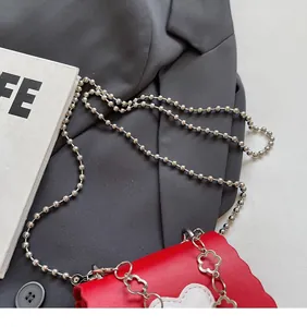 Detailed view of a red heart-themed crossbody bag with decorative silver bead chain