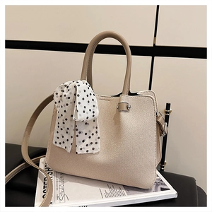 Détail d'un sac cabas tissé beige avec foulard à pois et bandoulière en cuir