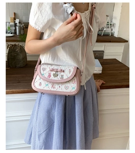 Detail of pink bow and heart charm on printed crossbody bag with floral pattern