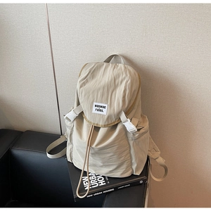 Detail view of beige nylon backpack with buckle closure and stylish fabric label