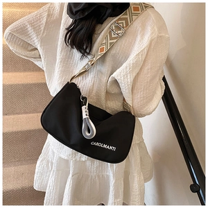 Détail du sac bandoulière noir en demi-lune avec sangle à motifs et logo blanc