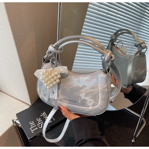Detail of silver metallic hobo bag with cloud texture, heart pearl and bow charms