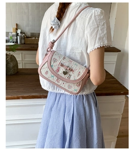 Sweet ballet crossbody bag with pink bow and floral prints on a kitchen setting model