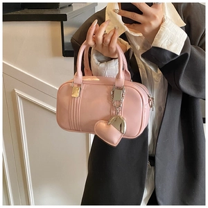 Pink glossy bowling bag with round top handles and cute metal heart pendant detail