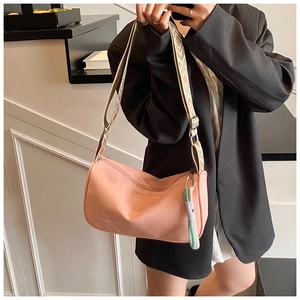 Sac demi-lune rose avec bandoulière géométrique large et franges sur le mannequin