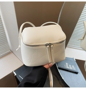 Detailansicht der cremeweißen Litschi-Textur und des Doppelreißverschlusses der Mini-Tasche