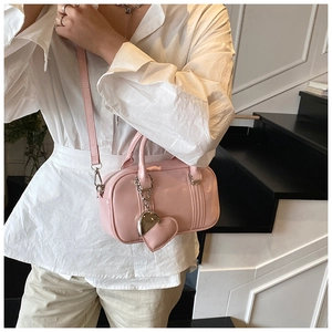 Pink Boston style handbag with heart charm detail and adjustable strap on a model