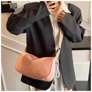 Détail d'un sac bandoulière rose en nylon avec sangle à motifs et pendentif bleu