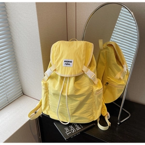 Detail of yellow crinkle nylon backpack showing drawstring closure and buckle
