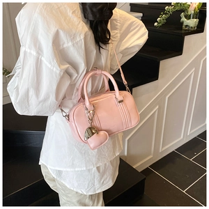 Detail showing pink leather bowling bag with heart charm and brand logo engraving