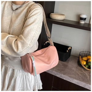 Détail du sac polochon en nylon rose avec bandoulière tissée et pendentif décoratif
