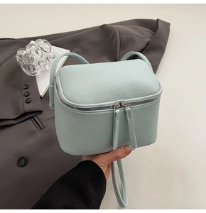 Detail der hellblauen Crossbody-Tasche mit Litschimuster-Textur und silbernen Reißverschlüssen