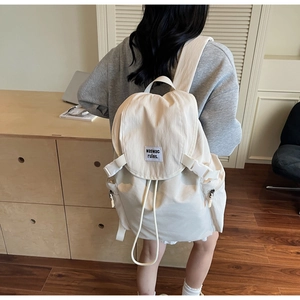 Rear view of a model wearing the cream white canvas backpack with stylish buckle straps