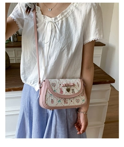 Detail of sweet pink crossbody bag featuring white heart-bear print and pink bow decoration