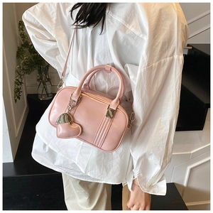 Close-up of pink leather Boston bag featuring parallel stitching and heart pendant charm