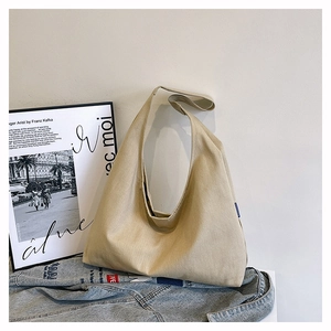 Detail view of large beige canvas hobo tote with wide strap and blue woven label