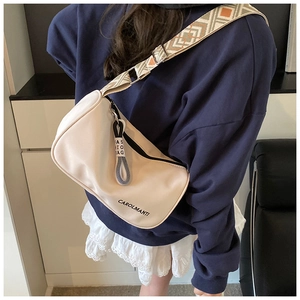 Détail d'un sac bandoulière beige demi-lune avec bandoulière jacquard porté par un modèle