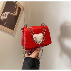 Close-up of red mini flap bag with heart patch and unique floral metal chain strap