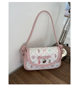 Detail of cute pink bow on printed shoulder bag with heart pendant and doll house patterns
