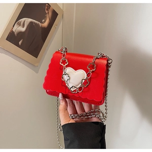 Detail of red mini crossbody bag featuring heart motif and floral chain strap