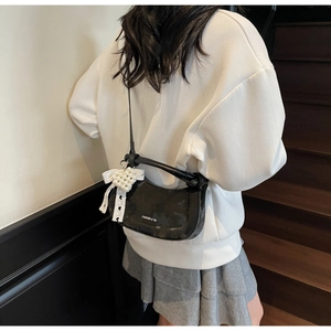 Detail of black crescent leather handbag with pearl heart charm and lace ribbon