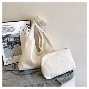 Detail of minimalist cream canvas tote bag set with a matching zipper pouch on denim