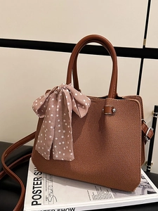 Sac seau tissé marron caramel élégant avec foulard à pois roses sur fond de magazine moderne