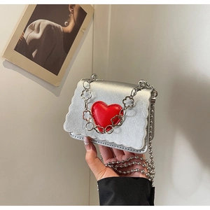 Close-up of silver mini bag with wavy scalloped edges and a 3D red heart decoration