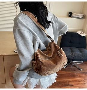 Brown canvas hobo bag with wide shoulder strap shown on a model in a cozy indoor setting