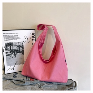 Detail of soft pink canvas tote bag showing wide shoulder strap on a denim jacket