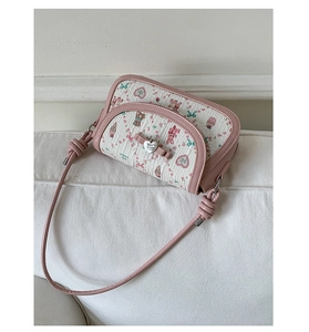 Detail of pink bow and silver heart pendant on a floral patterned crossbody bag