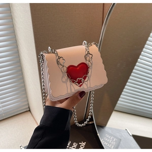 Detail of pink bag with scalloped edge, red heart, and floral petal silver chain link